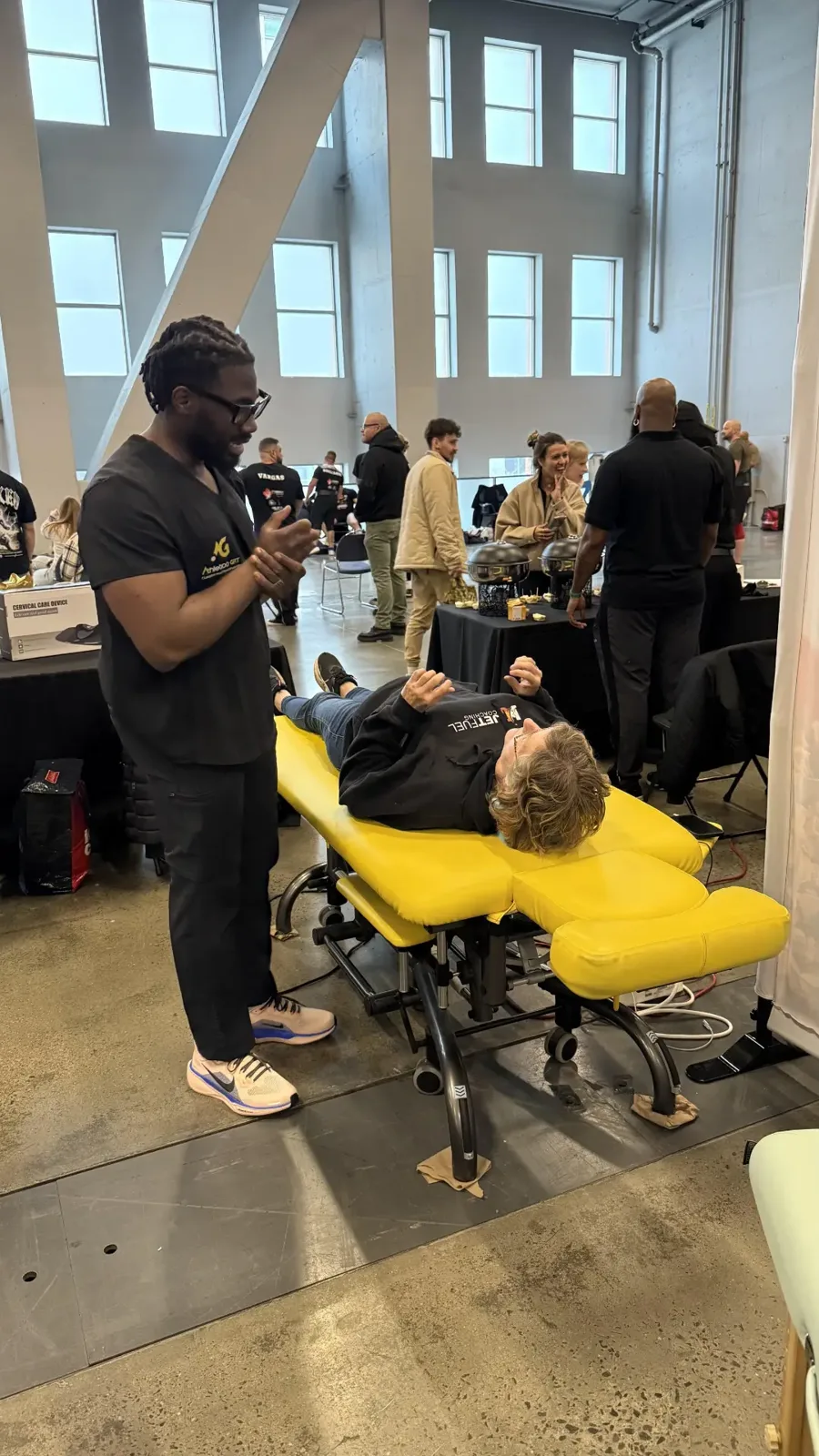 Athletico GFIT therapist treating a client on a yellow recovery table at an event