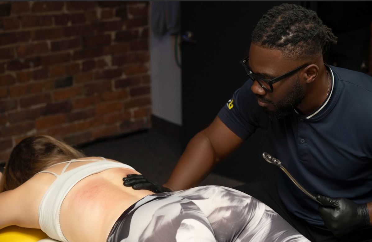 Thérapeute appliquant un instrument de mobilisation des tissus sur le dos d'une cliente